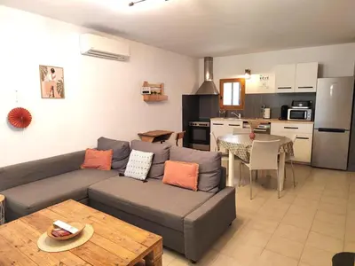 a living room with a couch and a table and a kitchen at Gîte des deux platanes in Orgon