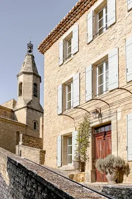a brick building with a tower and a red door at Hotel Crillon le Brave in Crillon-le-Brave