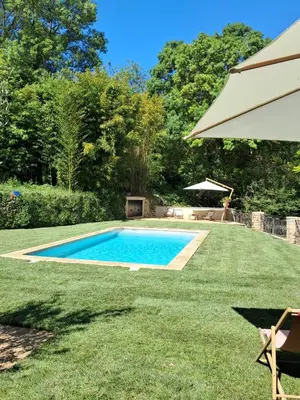 a swimming pool in a yard with an umbrella at Le Vieux Moulin de Jouques in Jouques