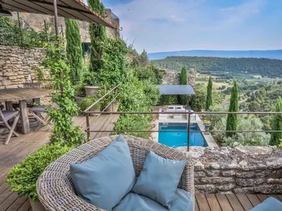 a patio with a wicker rattan couch on a wooden deck at Villa Sunset in Gordes in Gordes