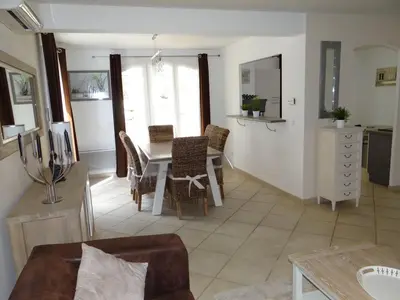 a kitchen and living room with a table and chairs at Golf de Pont Royal Villa du Lac climatisée 3 chambres Piscine chauffée Parking et Garage in Mallemort
