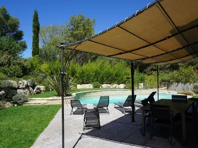 a table and chairs under an umbrella next to a pool at Golf de Pont Royal Villa du Lac climatisée 3 chambres Piscine chauffée Parking et Garage in Mallemort