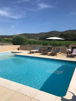 a blue swimming pool with chairs and an umbrella at Maison d'hôtes Bastide St Victor à 2,5 kilomètres de Lourmarin in Puyvert