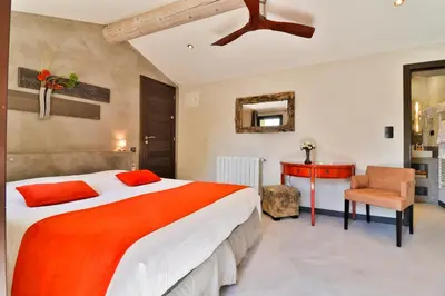 a bedroom with a large bed and a chair at Le Mas de la Lombarde in Lourmarin