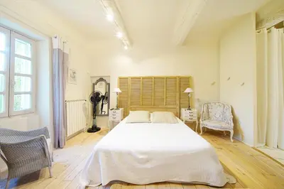 a bedroom with a large white bed and two chairs at Mas des Baussiers in Saint-Martin-de-Castillon