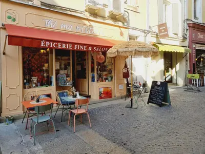 a store with tables and chairs and an umbrella on a street at Escapades en Ventoux in Venasque