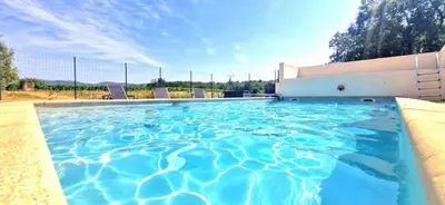 a swimming pool with blue water in front of a building at Escapades en Ventoux in Venasque