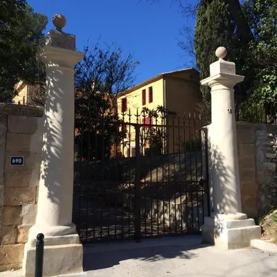 a black gate with two white pillars next to a fence at B&B Villa Roumanille in Aix-en-Provence