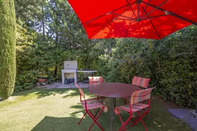 a table and chairs with a red umbrella at Villa Enzo in Orgon