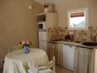 a kitchen with a table with a vase of flowers on it at La Guéritaulde in La Tour-dʼAigues