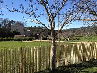 a fence with a tree in front of a field at Bastide de Fanny in Rognes