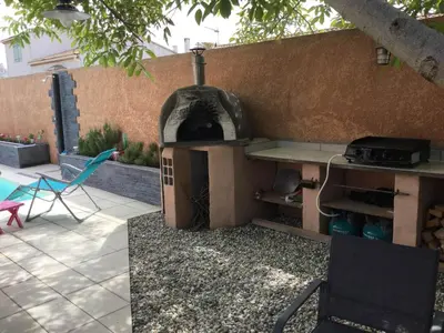 a outdoor grill with a table and a chair at Beautiful provencal vacation rental in L'Isle sur la Sorgue in LʼIsle-sur-la-Sorgue