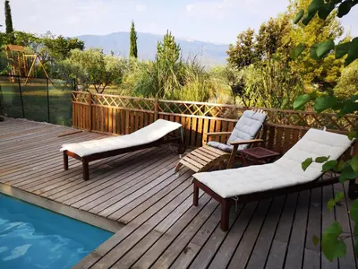 a wooden deck with two chairs and a pool at La Bastide du Limon in Mormoiron