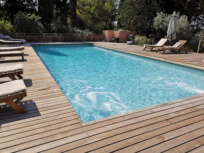 a swimming pool with chairs and a wooden deck at La Bastide du Limon in Mormoiron