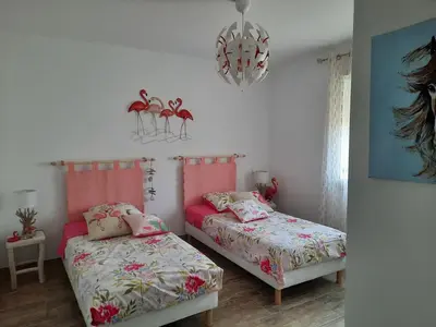 a bedroom with two beds and a chandelier at A pretty family house located in a tranquil area with a pretty view of the Luberon range. in Les Taillades