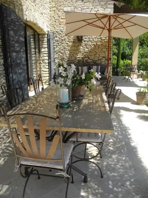 a wooden table with chairs and an umbrella at OUSTAU DE PIERA in Gordes