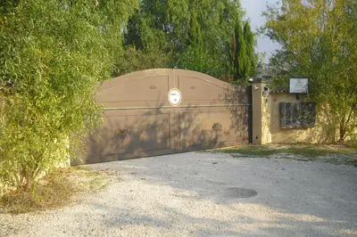 a large wooden gate in a driveway with trees at Lou mas li Pitchoun 