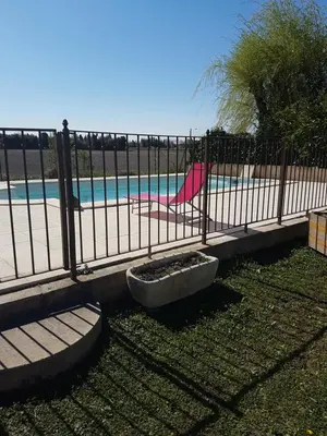 a fence in front of a beach with a pool at fleur de garance in Le Thor