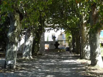 an avenue of trees with a statue in the distance at Le Moulin Des Ocres in Apt