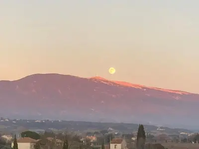 a moon rising over a mountain with a city at LA RESPELIDANE in Caromb