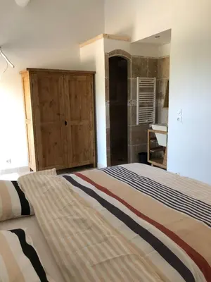 a bedroom with a large bed and a bathroom at Mas Eléhis Gîtes en Provence in Pernes-les-Fontaines