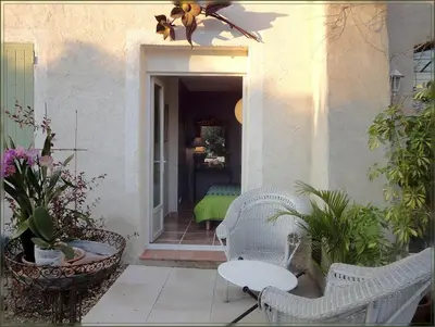 a patio with a white wicker chair and a table at La Gourmandine in Saint-Andiol
