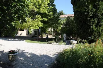 a garden with a statue and trees and a building at Gite La Gourmandine in Saint-Andiol