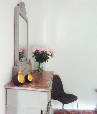 a table with a vase of flowers and a mirror at Fontaine-de-Vaucluse : maison avec vues in Fontaine-de-Vaucluse