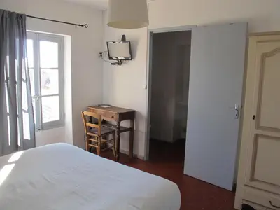 a bedroom with a bed and a desk and a window at Le Guintrand in Bédoin