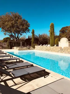 a swimming pool with chairs and blue water at Bastidon à Gordes avec piscine in Gordes
