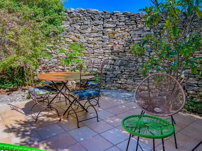 a living room with a table and chairs and a balcony at Bastidon à Gordes avec piscine in Gordes