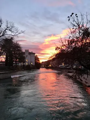 a view of a river with a sunset in the background at Petit Rêve in LʼIsle-sur-la-Sorgue