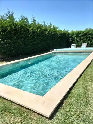 a swimming pool with two chairs in the grass at Villa Zénitude in Cabannes