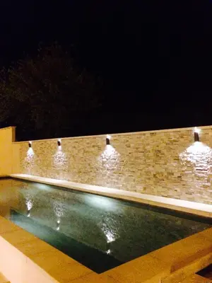 a swimming pool with lights on a brick wall at chez nico in Bédoin