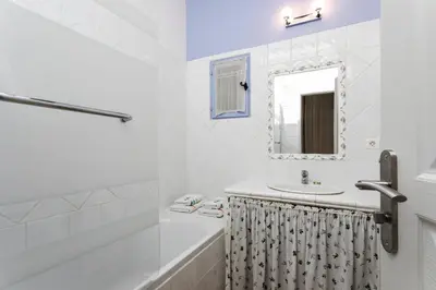 a white bathroom with a sink and a mirror at Gîtes Domaine des Machottes in Grans