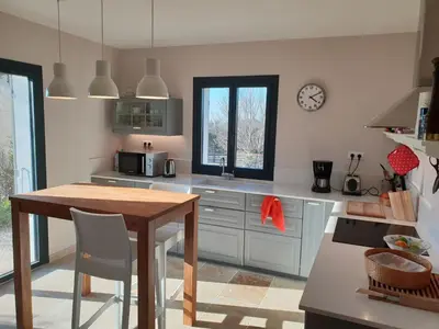 a kitchen with a table and a clock on the wall at le Gecko en Provence in La Roque-sur-Pernes