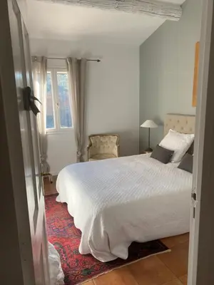 a bedroom with a white bed and a window at Villa des Roses in Roussillon