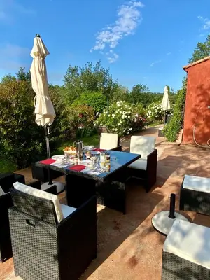 a patio with a table and chairs and an umbrella at Villa des Roses in Roussillon