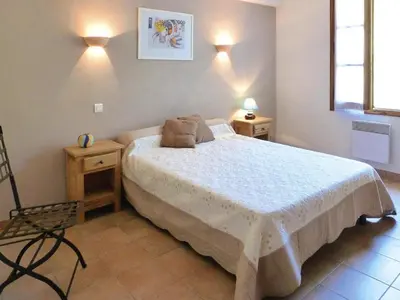 a bedroom with a bed and two tables and a chair at Ménerbes Home with Private Pool in Ménerbes