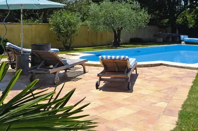 two chairs and an umbrella next to a swimming pool at Cozy Noves Home with Pool Access in Noves