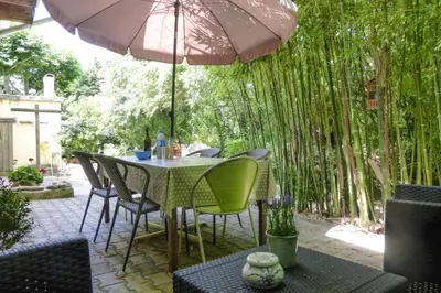 a table and chairs under an umbrella on a patio at Cozy Noves Home with Pool Access in Noves