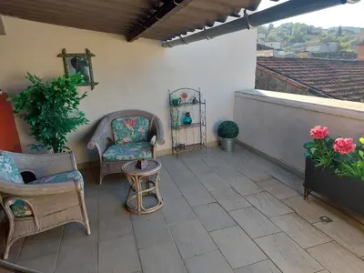 a patio with two chairs and a table and flowers at Côté Terrasse in Apt