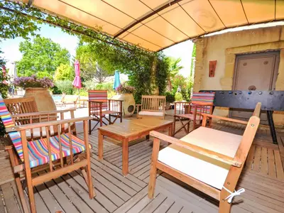 a patio with tables and chairs on a wooden deck at Holiday Home L'Olivier by Interhome in Lagnes