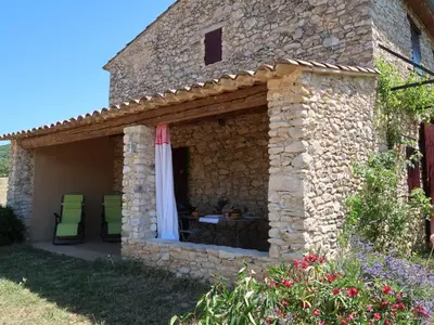 a stone house with a patio with a table and chairs at Holiday Home Les Geais by Interhome in Saint-Saturnin-les-Apt
