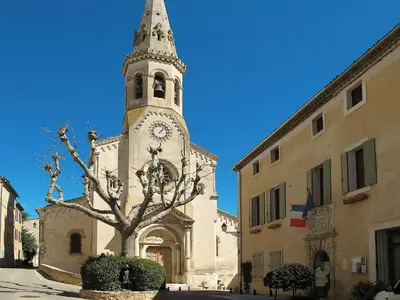 a church with a tall tower with a clock on it at Holiday Home Les Geais by Interhome in Saint-Saturnin-les-Apt