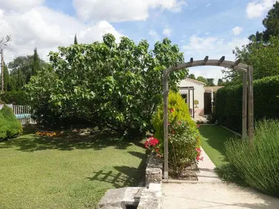 a garden with an arch and flowers in a yard at Apartment Haider by Interhome in Caumont-sur-Durance