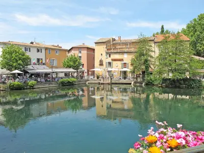 a river in a town with flowers and buildings at Apartment Haider by Interhome in Caumont-sur-Durance