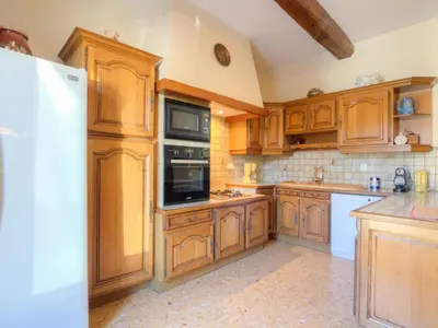 a kitchen with wooden cabinets and a refrigerator at Holiday Home de la Roque by Interhome in Althen-des-Paluds