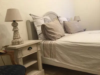 a bed with pillows and a table with a lamp at Mas de Nonin St Rémy de Provence in Noves
