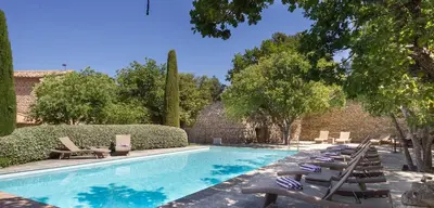 a swimming pool with lounge chairs next to a brick wall at Le Jas de Gordes in Gordes